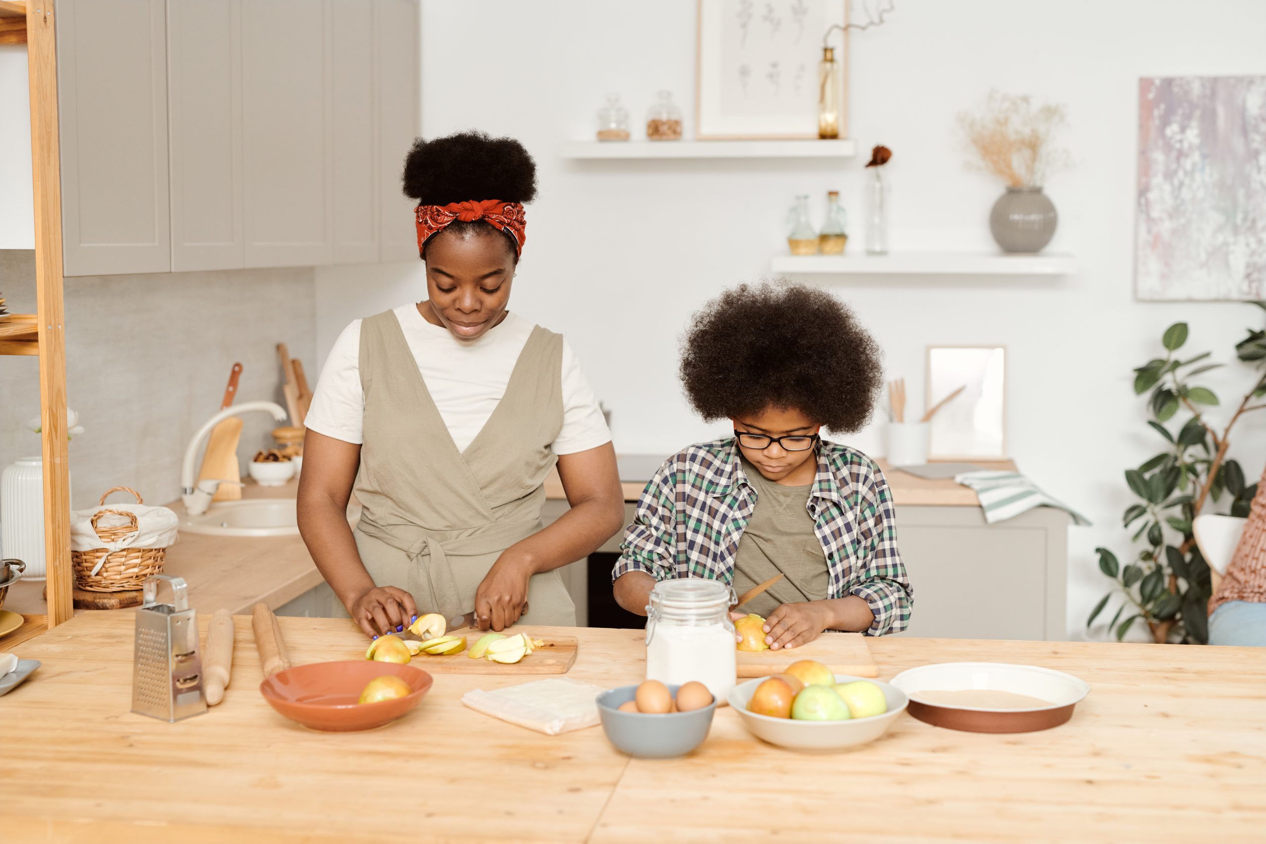 Cute little boy helping his mom with cooking lunch in the kitchen